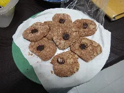 Sugar-coated pastries with a raisin in the center on a plate with paper.
