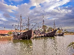 Three wooden ships in the water at Palos de la Frontera.