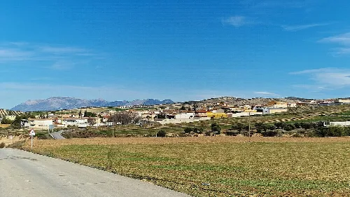 Landschaft mit Dorf und Bergen im Hintergrund.