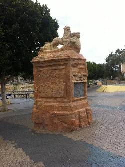 Escultura de un león en una base de piedra en un paseo de Murcia.
