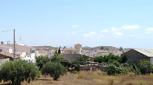 Paisaje del pueblo de Los Gallardos con casas, vegetación y colinas.