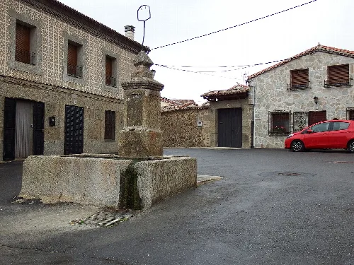 Brunnen auf einem Platz in San Miguel de Corneja mit Steinhäusern.
