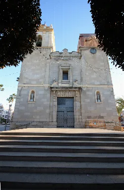 Stone church facade with bell tower and stairs in Benejúzar.