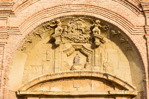 Church facade with sculptures and stone arch in Munébrega.