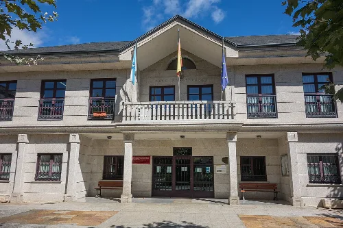 Hellfarbenes zweistöckiges Gebäude mit Flaggen an der Fassade.