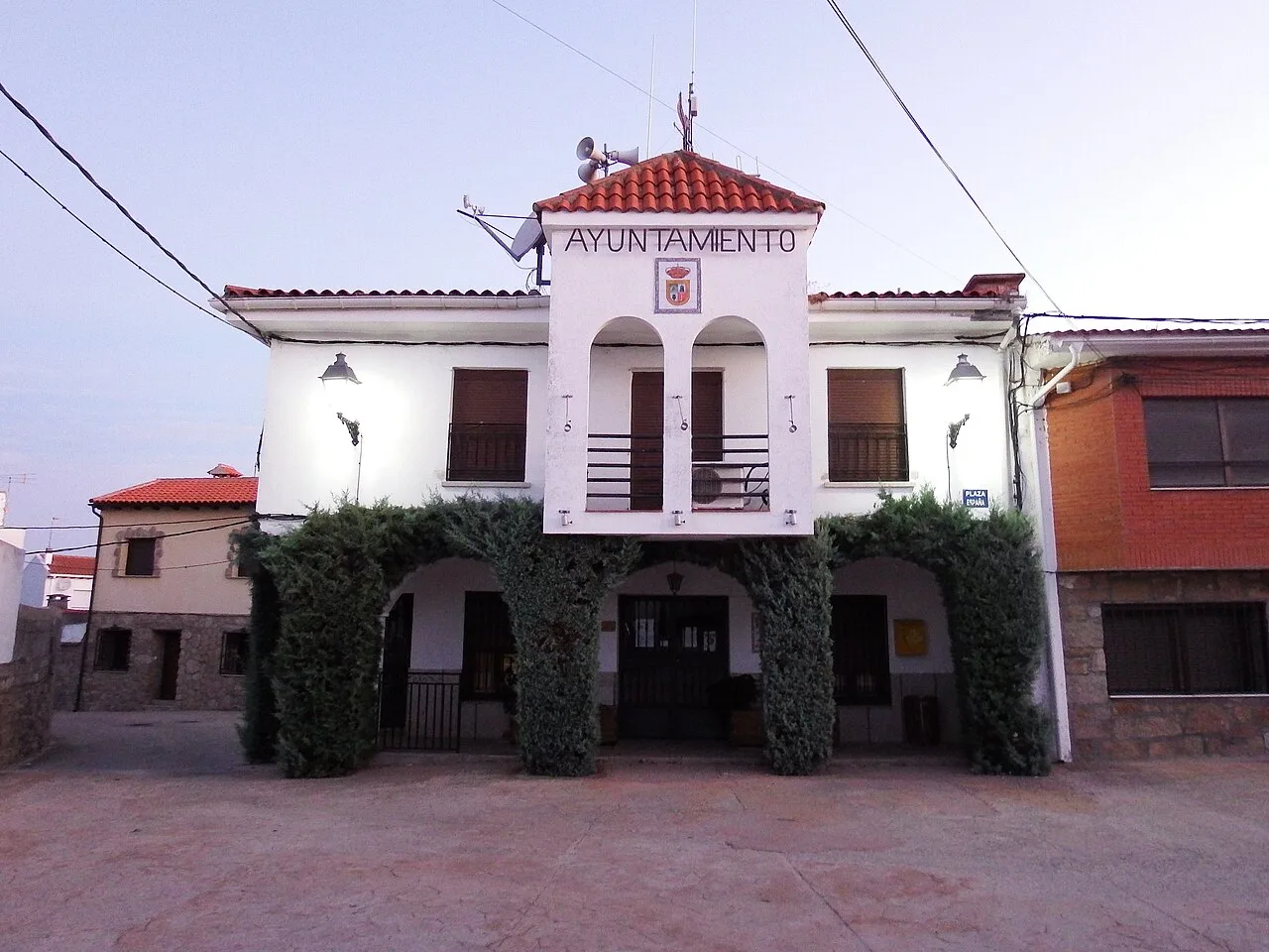 Town hall with white facade and greenery at the entrance.