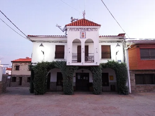 Town hall with white facade and greenery at the entrance.