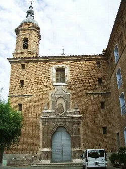Brick church facade with bell tower on the left and stone details at the entrance.