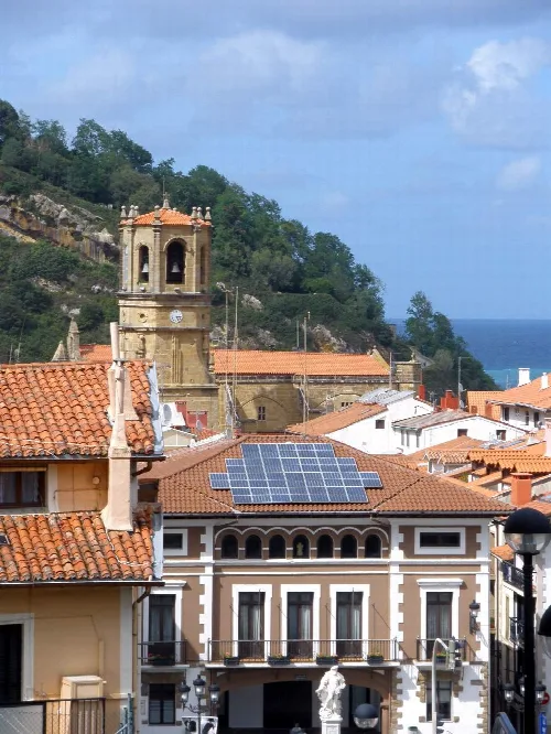 Häuser mit Ziegeldächern und Solarpaneelen, Kirche und Meer im Hintergrund in Guetaria.