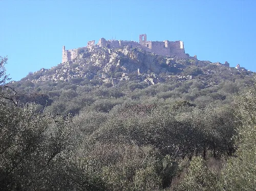 Blick auf das Schloss Calatrava auf einem Hügel mit Vegetation.
