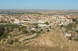 Vista panorámica de Caspe con casas, colinas y río en el fondo.