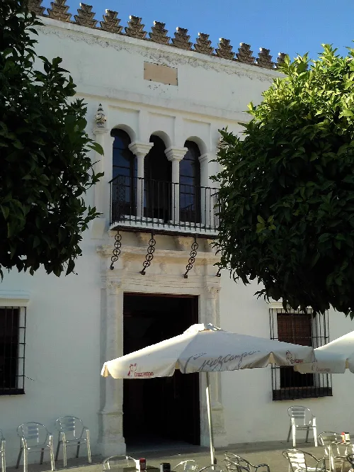 Puerta de un palacio con pórtico de mármol y ventanas con arcos en Olivares, Sevilla.