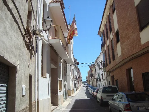 Vista de una calle estrecha con edificios y coches en Figueroles.
