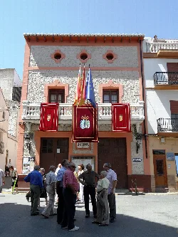 Gebäude mit Flaggen und Menschen auf dem Platz in Fuente la Higuera.