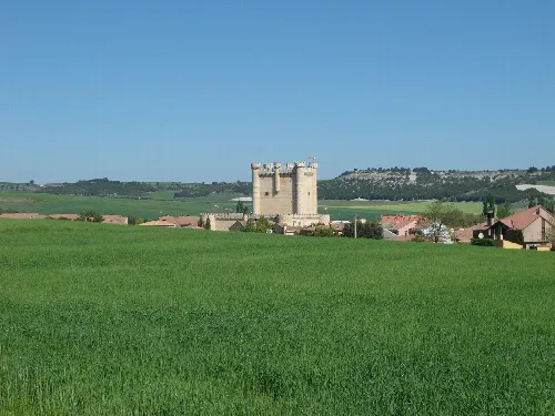 Castillo en Fuensaldaña con campos verdes y cielo azul.