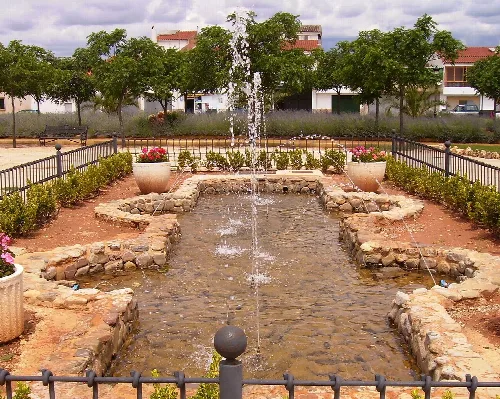 Wasserbecken mit Springbrunnen und Bäumen in einem Park in Arroyo del Ojanco.