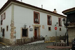 Building with white facade, wooden windows, and street sign.