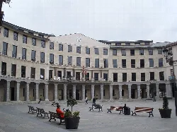 Herrizo-Platz mit Bänken, Menschen und dem Rathaus von Llodio.