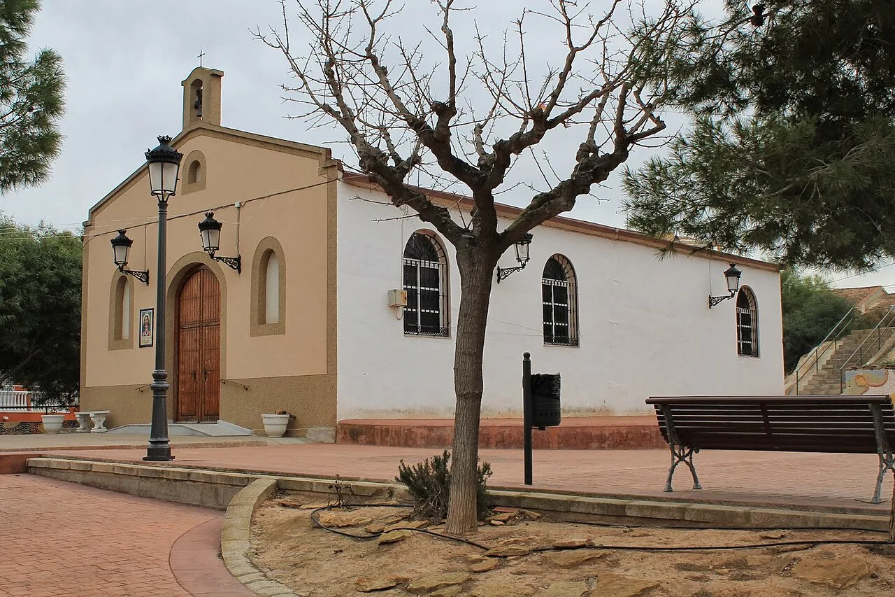 Ermita blanca con puerta de madera y ventanas en El Mojón, Murcia.