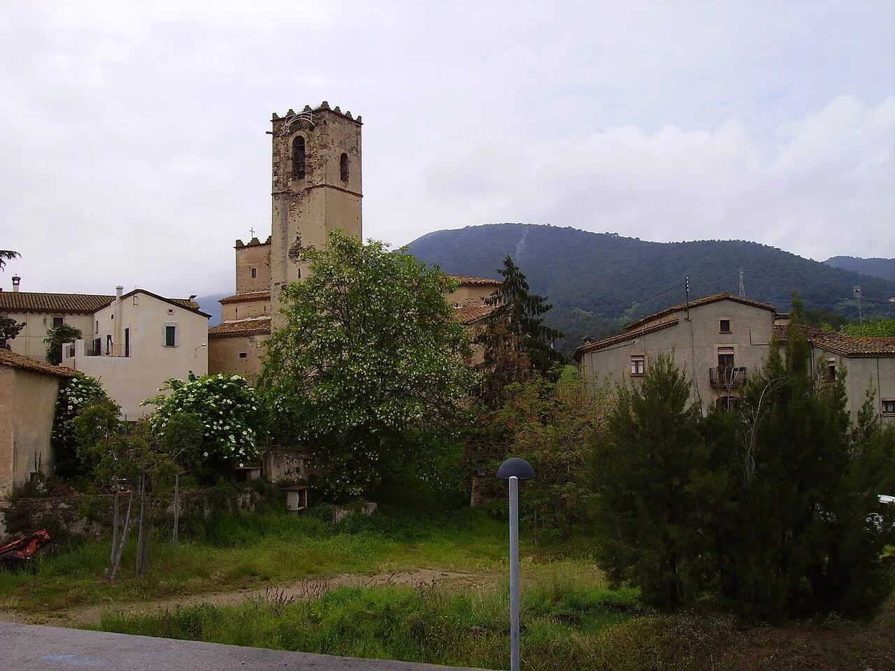Vista de la iglesia de Sant Muç en Cànoves, con casas y árboles alrededor.
