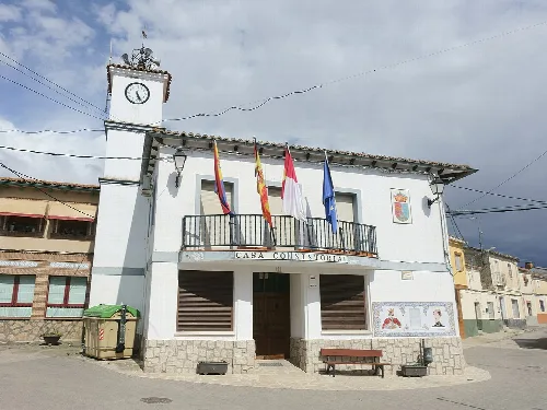 White building with a clock tower and flags on the facade.
