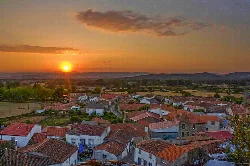 View of houses and fields with the setting sun on the horizon.