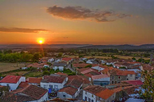 View of houses and fields with the setting sun on the horizon.