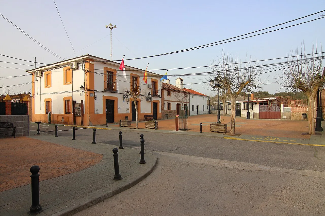 Rathausplatz mit Gebäuden, Flaggen und Bäumen in Cardiel de los Montes.
