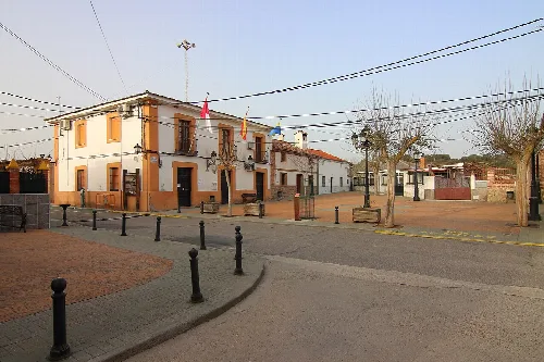 Rathausplatz mit Gebäuden, Flaggen und Bäumen in Cardiel de los Montes.