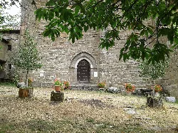 Stone hermitage door with trees and flowers around.