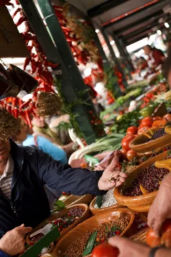 Puerta de mercado con puestos llenos de frutas y verduras en Gernika.