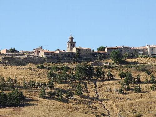 Blick auf eine Hügelstadt mit Kirche und Häusern unter blauem Himmel.