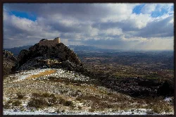 View of a castle on a hill and a town in the valley with cloudy sky.