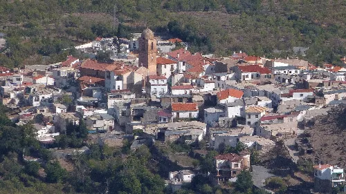 Luftaufnahme eines Dorfes mit weißen Häusern und einer Kirche im Zentrum.