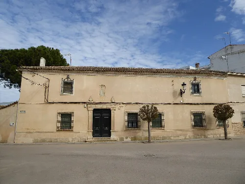 Altes Haus mit vergitterten Fenstern und Bäumen auf dem Bürgersteig in Santa María del Campo Rus.