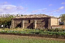 Stone church in Huércanos with surrounding vegetation and fields.