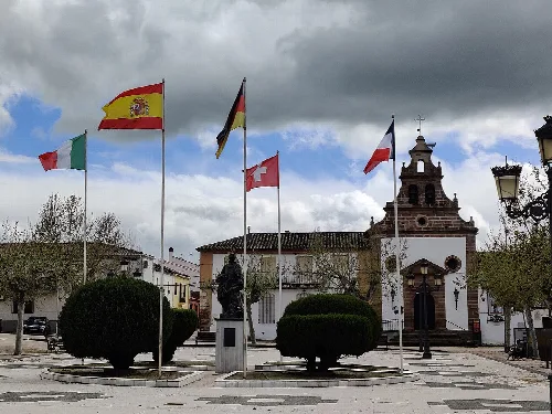 Flaggen auf dem Platz mit Kirche und Statue in Santa Elena, Jaén.
