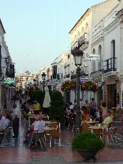 Plaza larga con terrazas y gente en Cartaya, Huelva, en un día soleado.