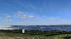 Reihen von Solarpanelen in einem Feld unter einem blauen Himmel mit Wolken.
