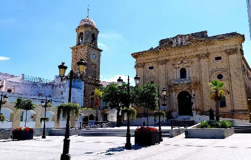 Platz mit Kirche, Uhr und Bäumen in Chiclana de la Frontera.