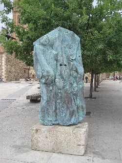 Escultura de un cofrade en Astorga, hecha de madera y en un espacio público.