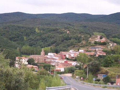 View of the town with houses, church, and green hills in the background.