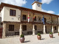 Town hall building with columns, flags, and clock in Lupiana.