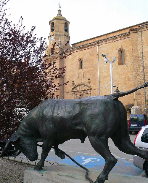 Bronzestatue eines Stiers mit Seil in Lodosa, Navarra, vor einer alten Kirche.