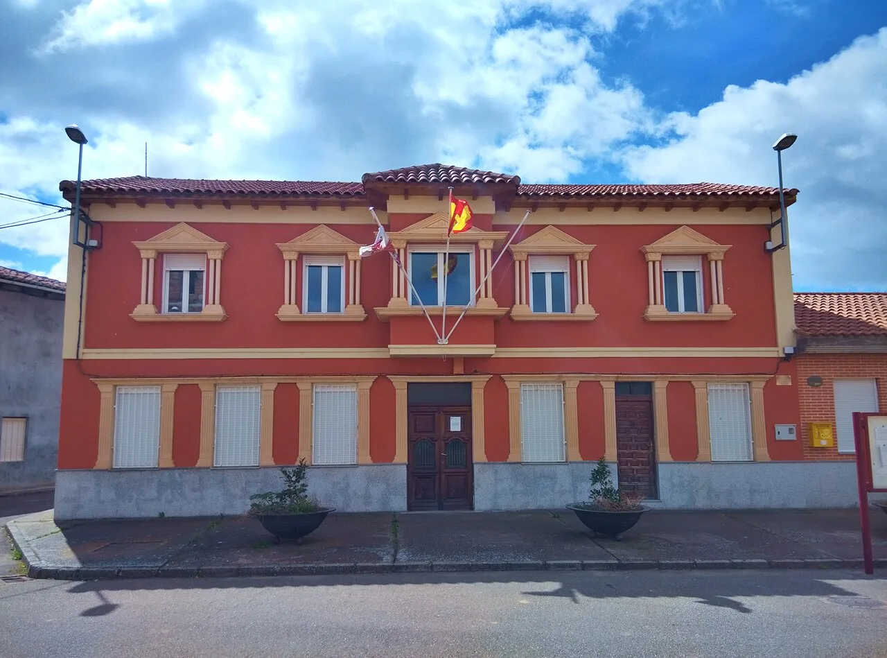 Edificio del Ayuntamiento de Quintana del Marco con fachada terracota y banderas en la parte superior.