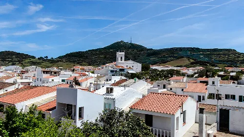 Blick auf weiße Häuser und grüne Hügel in Mercadal, Menorca.