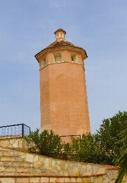 Torre de color terracota con ventanas y tejado de tejas en Arboleas.