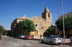 Square and parish church of Cordobilla de Lácara with parked cars.