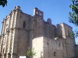 San Andrés Church in Zarza la Mayor with stone walls and historic structure.