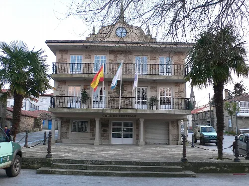 Dreistöckiges Gebäude mit Flaggen an der Fassade und Treppen davor.
